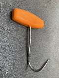 Metal hook with orange handle on a gray textured surface